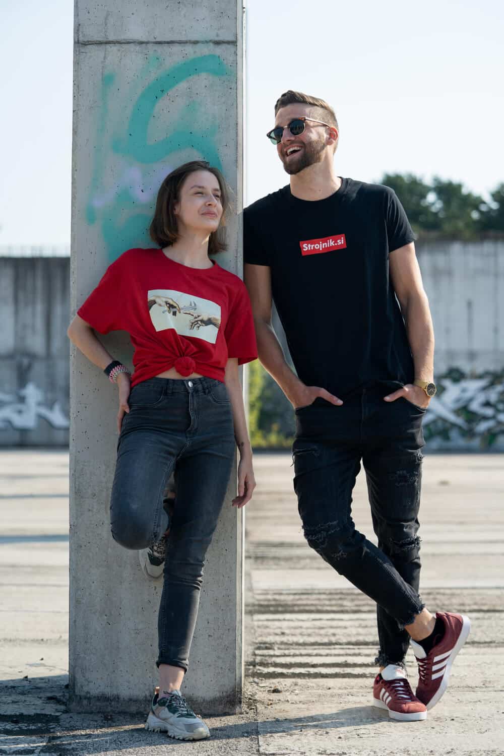 engineer-style-CNF8EdB58Vc-unsplash | Peru Travel Blog Two casually dressed friends leaning against a graffiti-covered concrete pillar in an open lot, smiling at each other.