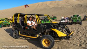 A couple get set to ride in a dune buggy for sandboarding in Huacachina