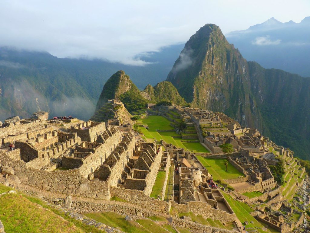 Machu Picchu with small groups of tourists scattered sporadically across the sprawling ruins. 
(Photo by LoggaWiggler on Pixabay)