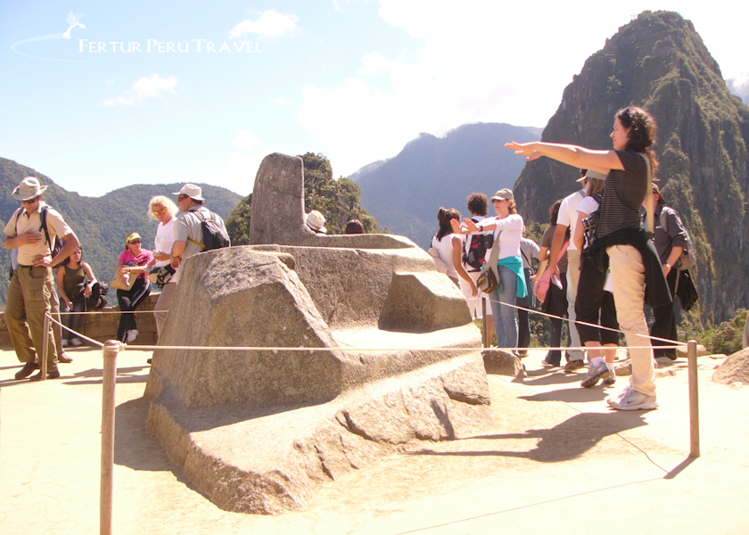 Tourists pass the Intihuatana during their Machu Picchu Tour, and several stop to reach out and feel its cosmic energy