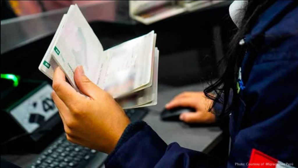Immigration official checking passport at Jorge Chavez International Airport
