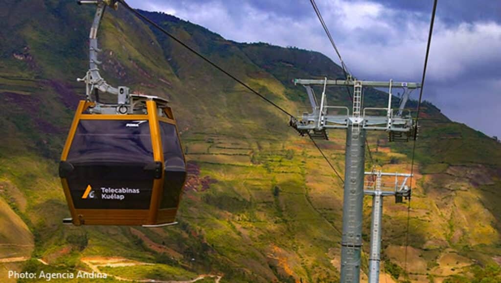 Telecabinas Kuélap Gondola in Flight — Cable Car Over the Utcubamba Valley, Peru | Peru Travel Blog A Telecabinas Kuélap golden gondola suspended in mid-air over the dramatic terraced hillsides and cloud forest landscape of the Utcubamba Valley in Amazonas, northern Peru, with a second cable car tower visible in the background. Photo: Agencia Andina.