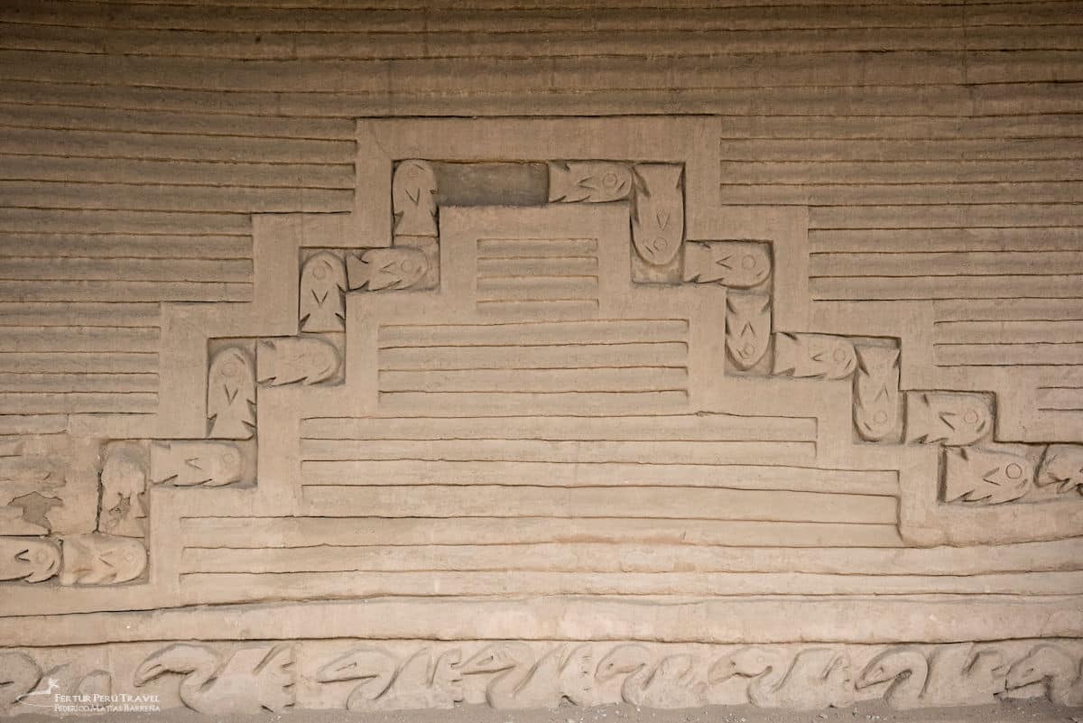 Chimú Adobe Frieze with Fish and Stepped Geometric Motifs at Chan Chan | Trujillo, Peru | Peru Travel Blog A close-up of an intricately carved adobe wall frieze at Chan Chan featuring a stepped pyramid motif surrounded by repeating fish figures and a wave border along the base, La Libertad, Peru