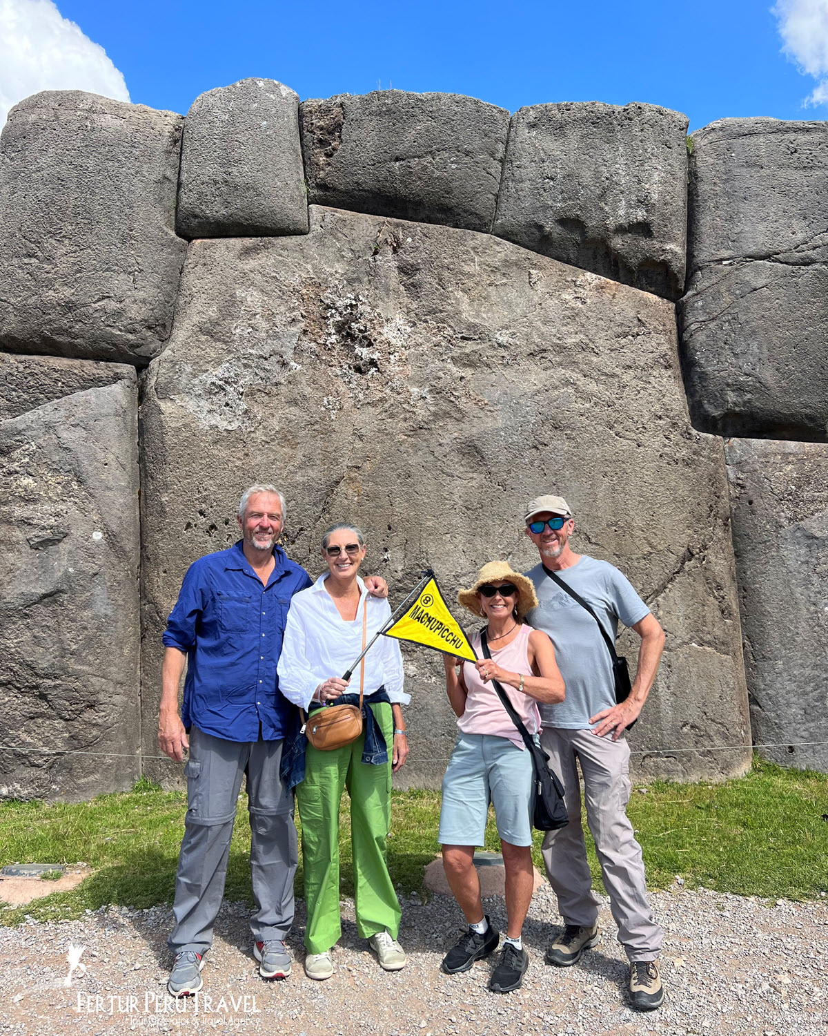Fertur Peru Travel Clients Posing Before the Massive Inca Walls of Sacsayhuamán, Cusco, Peru | Peru Travel Blog Four Fertur Peru Travel clients pose in high spirits before the iconic megalithic walls of Sacsayhuamán, the great Inca ceremonial fortress above Cusco. The massive interlocking limestone blocks, some weighing over 100 tons.