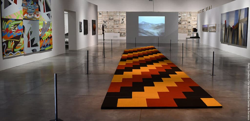 MAC Lima | Peru Travel Blog Art gallery in MAC Lima with a long orange‑black zigzag rug leading toward a projection screen and wall art on white walls.