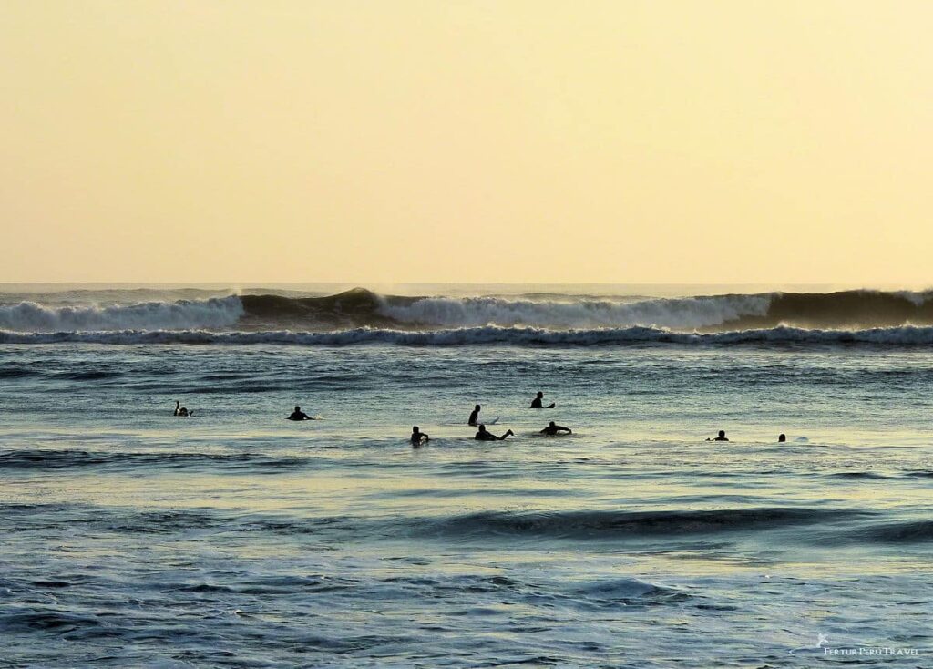 Surfers Waiting for Waves at Huanchaco Beach, Trujillo, Peru | Peru Travel Blog Silhouettes of surfers floating on calm water at dusk, waiting for breaking waves at Huanchaco Beach near Trujillo, Peru