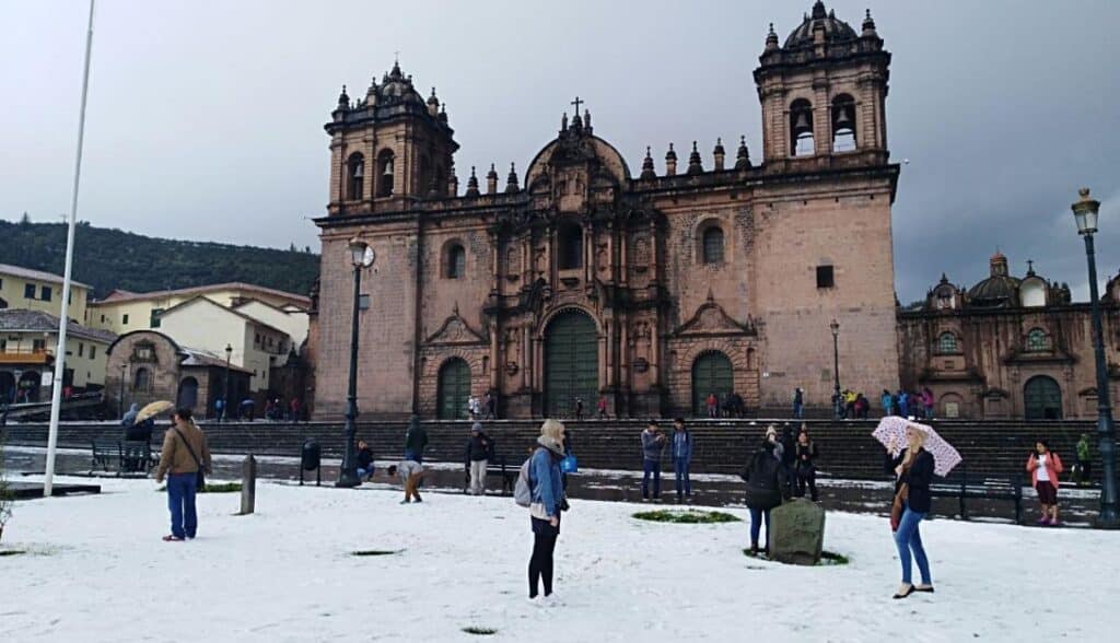 Aberrant weather in Cusco | Peru Travel Blog Visitors and locals stand on the hail-covered Plaza de Armas in front of the Cusco Cathedral in the aftermath of the November 18, 2017 hailstorm, several carrying umbrellas as light precipitation continues. Photo: Trome.
