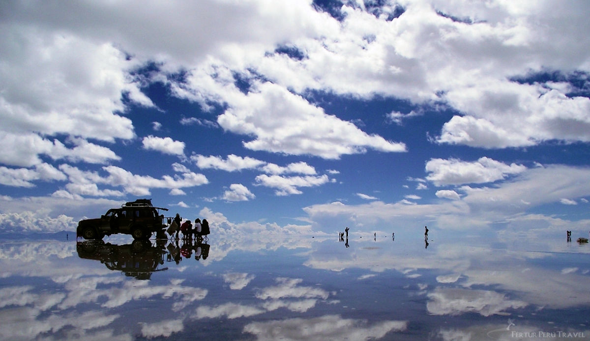 Perfect Sky Mirror Reflection on the Uyuni Salt Flats (Salar de Uyuni), Bolivia | Peru Travel Blog A surreal sky mirror effect on the flooded Salar de Uyuni salt flats in Bolivia, with a 4x4 vehicle and silhouetted tourists perfectly reflected in a thin layer of water creating a seamless illusion of sky above and below, Bolivia