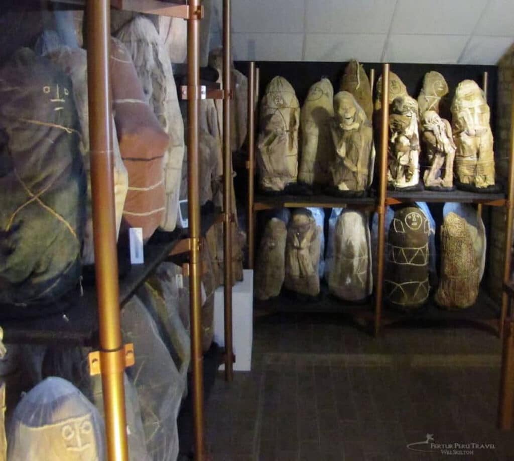 Chachapoyas Mummy Bundles at the Leymebamba Museum, Amazonas | Photo: Will Skelton | Peru Travel Blog Rows of ancient Chachapoyas mummy bundles displayed on tiered museum shelving at the Leymebamba Museum in Amazonas, Peru, with painted faces and wrapped textile coverings visible across multiple individuals. Photo credit: Will Skelton.