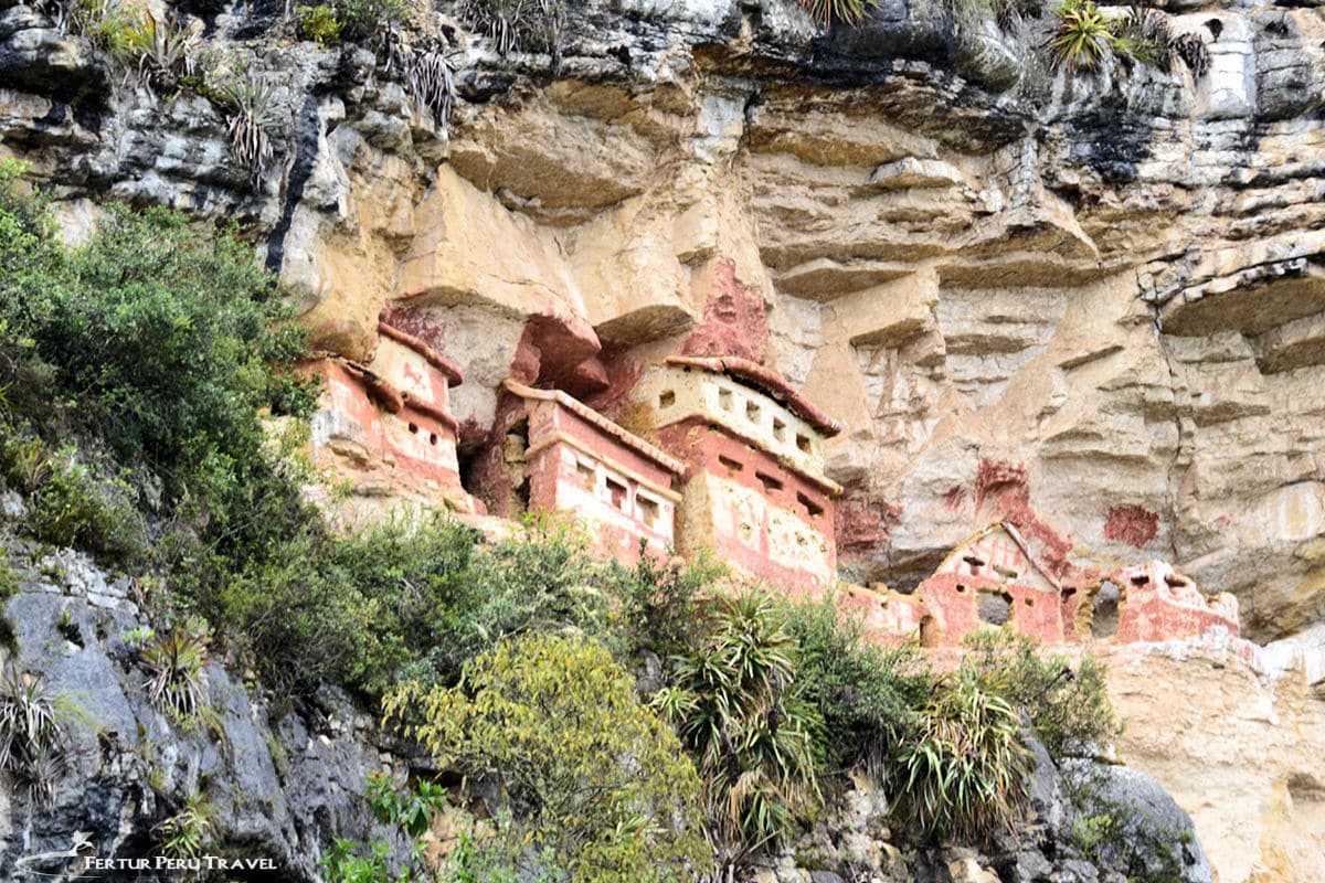 Revash Chachapoyas Cliff Mausoleums, Amazonas, Peru | Peru Travel Blog The distinctive red-painted stone mausoleums of Revash, tucked into a natural limestone cliff overhang in the Amazonas region of Peru, surrounded by cloud forest vegetation. Photo credit: Fertur Perú Travel.