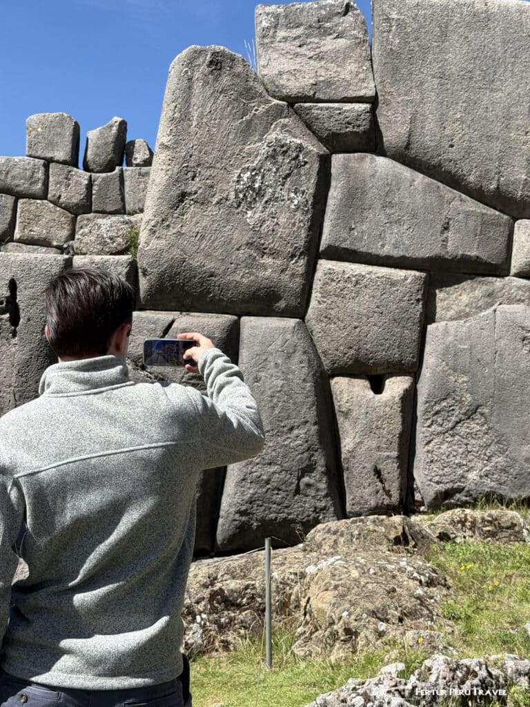 Massive Polygonal Stonework at Sacsayhuamán | Peru Travel Blog A traveler photographs the colossal, precisely fitted stone blocks of Sacsayhuamán's zigzagging walls on a sunny day in Cusco. Photo credit: Fertur Perú Travel.