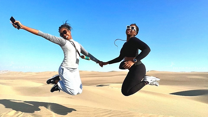 Two Fertur Peru Travel clients having fun on the sand dunes above the Huacachina Oasis before going on their dune buggy ride. 