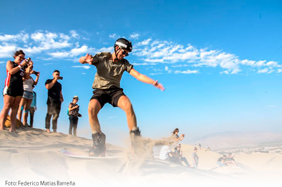 Lugares turísticos de Ica: Foto de las Dunas de Huacachina y deportista practicando Sandboarding.