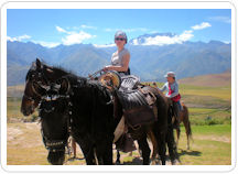 Dos mujeres montando caballos peruanos de paso en una excursión ecuestre en el Valle Sagrado de Cusco 