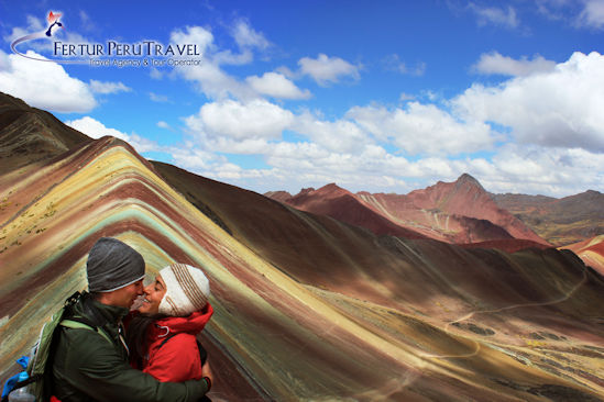 A beautiful couple celebrate with a hug upon reaching the top of Vinicunca - Rainbow Mountain, Cusco, Peru