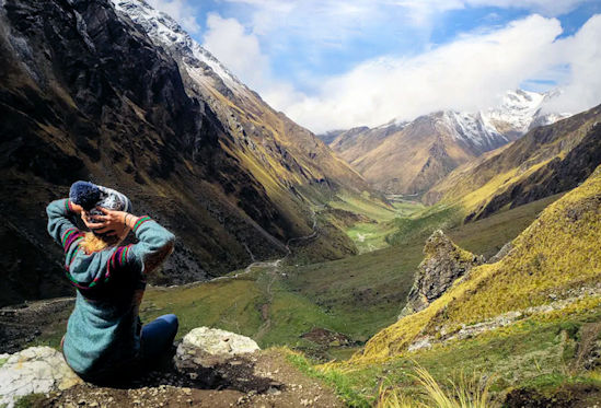Female traveler sits and takes in the view of Salkantay, one of one of the wonderful adventure tours in Peru