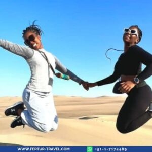 Jumping for joy in the sand dunes of Huacachina, Ica, Peru