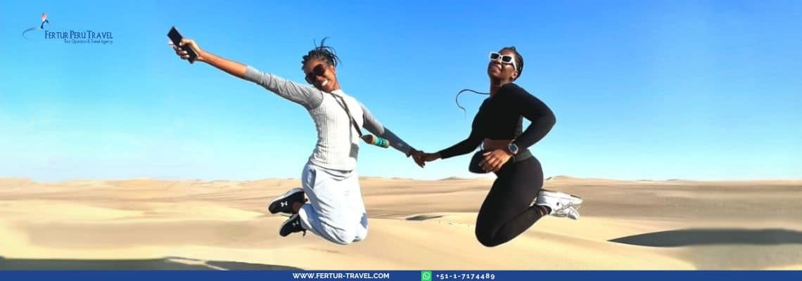 Jumping for joy in the sand dunes of Huacachina, Ica, Peru