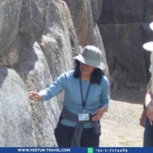 Guía profesional de Fertur Perú Travel explicando la técnica de la mampostería inca a una viajera frente a los imponentes muros de piedra de un sitio arqueológico en Cusco — la atención personalizada que usted recibirá en este tour de lujo de 4 días.