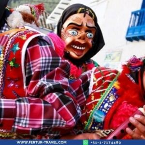 Traditional masked dancers at Paucartambo Festival wearing large character masks with exaggerated smiling faces and bright blue eyes, dressed in colorful plaid ponchos and traditional Andean textiles, performing in a street carnival setting