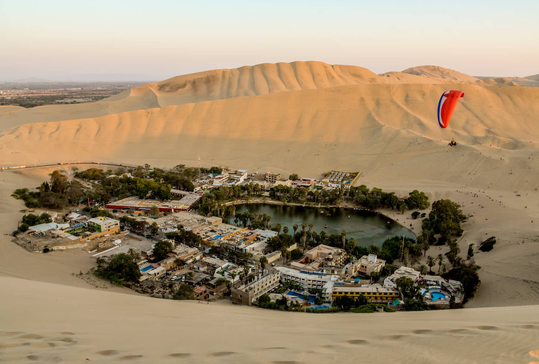 Parapente planea sobre el Oasis de Huacachina en Ica, Perú