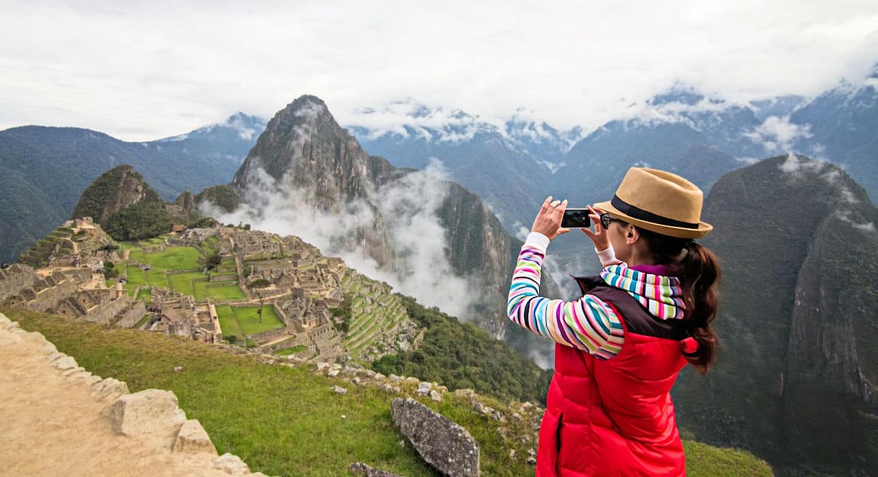 Female traveler taking the iconic photo of Machu Picchu