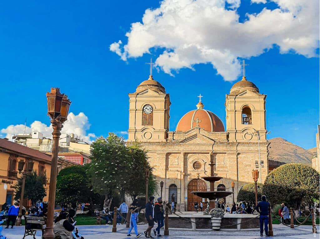 People relaxing in Plaza de la Constitución with the colonial Huancayo Cathedral and Andean mountains in the background, Huancayo, Peru