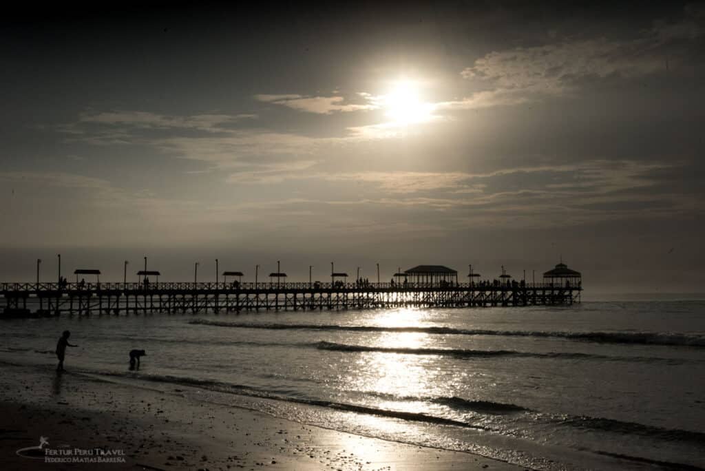 Huanchaco, a legendary beach resort near Trujillo where Chimú fishermen still navigate the waves on traditional reed boats (caballitos de totora), bathed in moonlight.